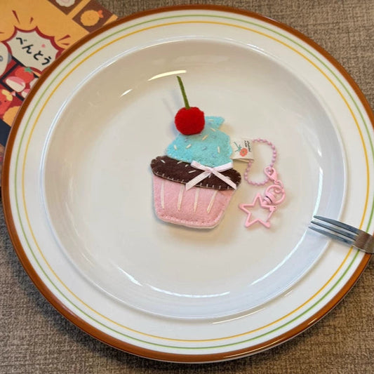 Decorative cupcake plushie on a plate with a fork, on a textured surface.
