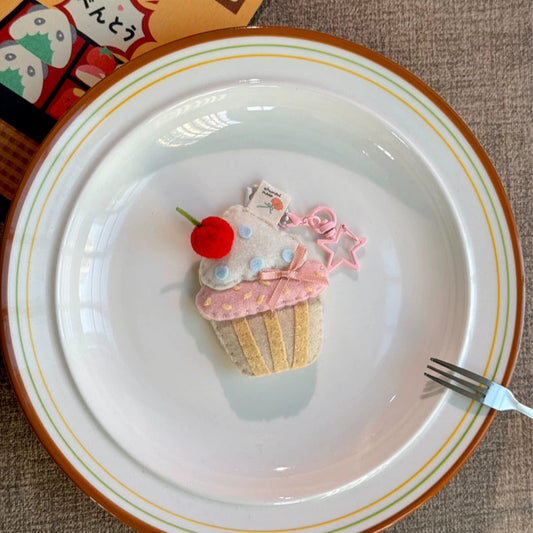 Decorative cupcake ornament on a white plate with a fork, on a textured surface.